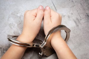 White Young Child’s Hands in Jail Handcuffs